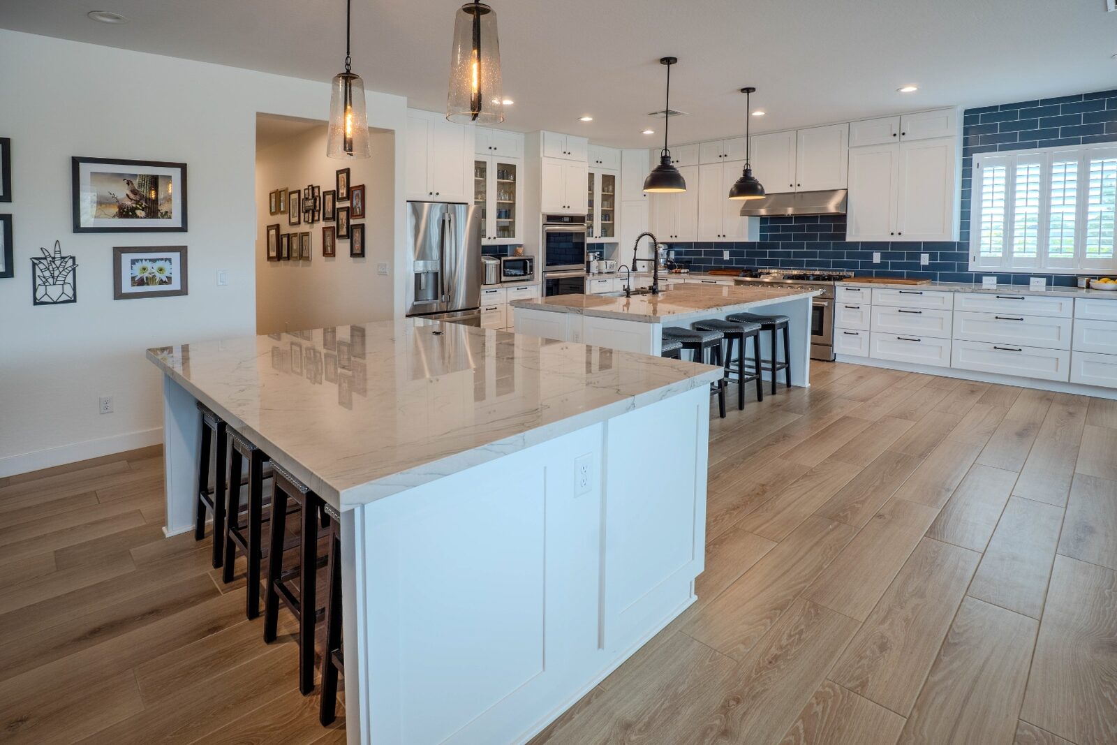 Luxury kitchen with dual islands, marble countertops and blue tile backsplash