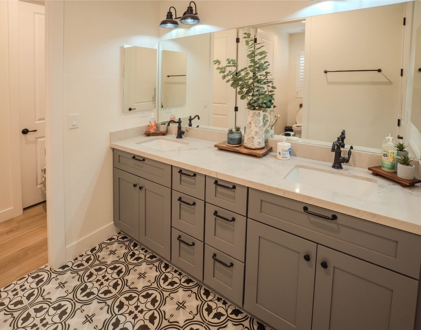 Double vanity bathroom with marble countertop and patterned tile floor