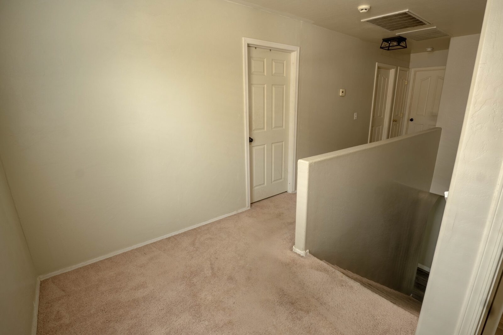 Upstairs hallway with carpeted floors and six-panel doors