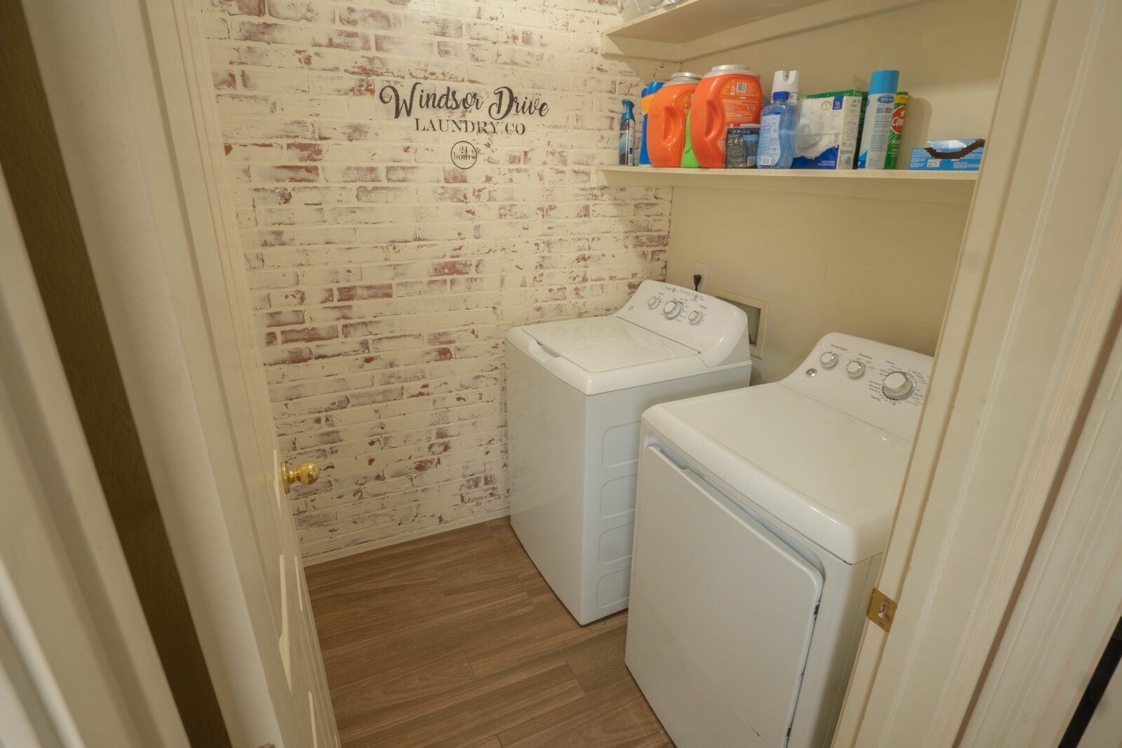 Styled laundry room with whitewashed brick wallpaper and full-size washer dryer