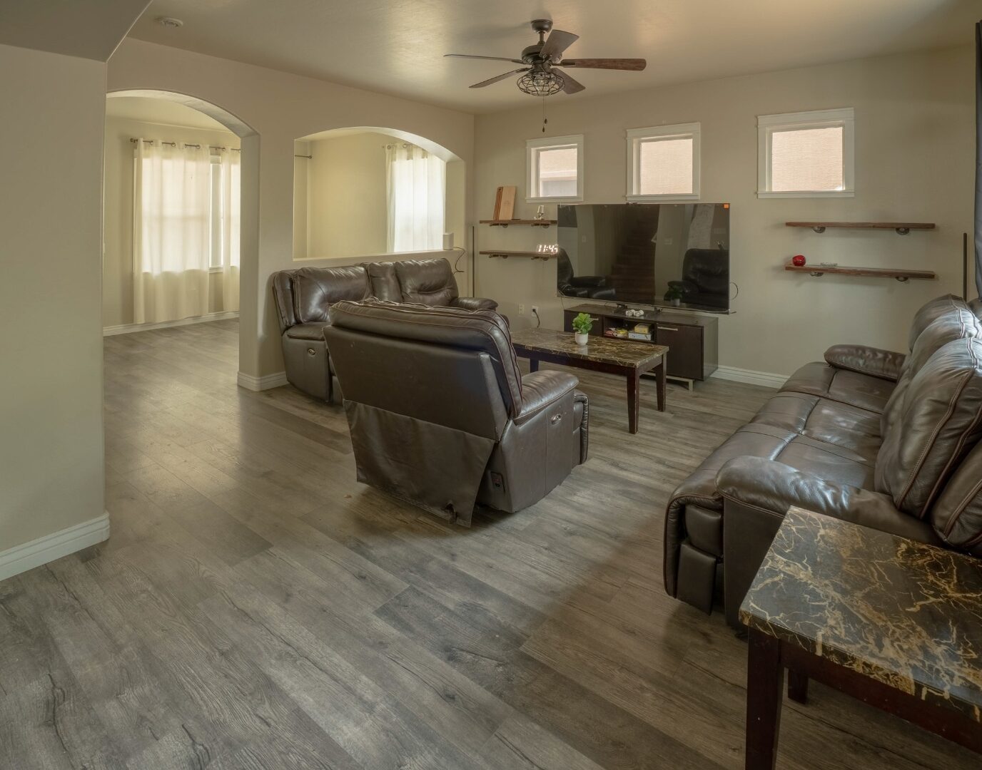 Open-plan living room with arched doorways and ceiling fan